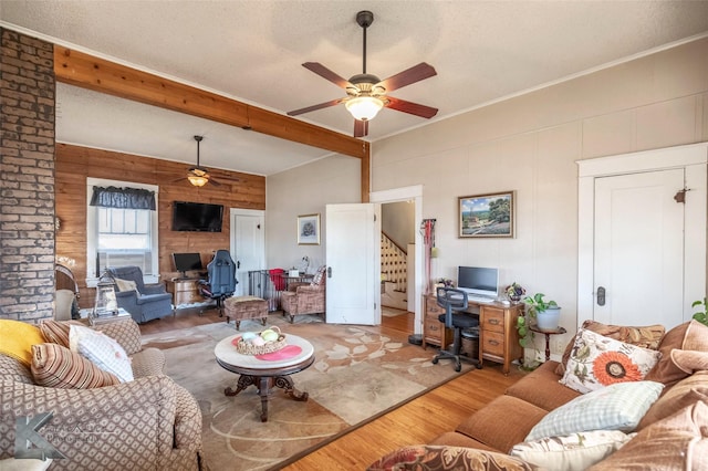 living room featuring beam ceiling, a textured ceiling, a ceiling fan, and light wood finished floors