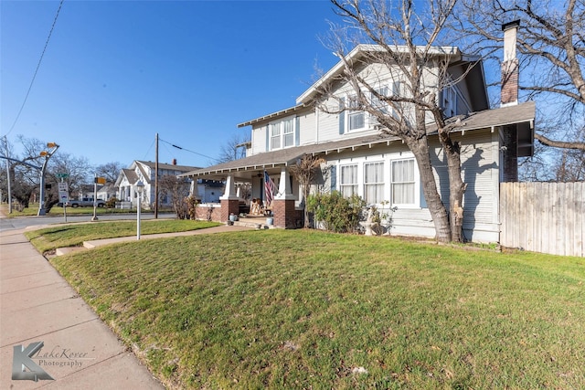 view of front of home featuring a porch, a chimney, a front lawn, and fence