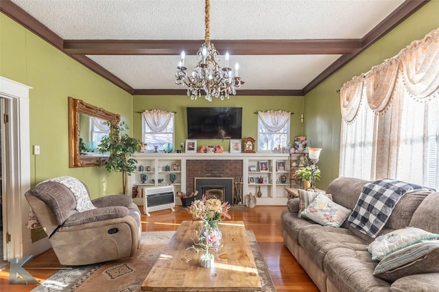 living area with a healthy amount of sunlight, beamed ceiling, wood finished floors, and a textured ceiling