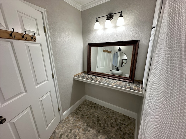 bathroom featuring crown molding, baseboards, and a textured wall