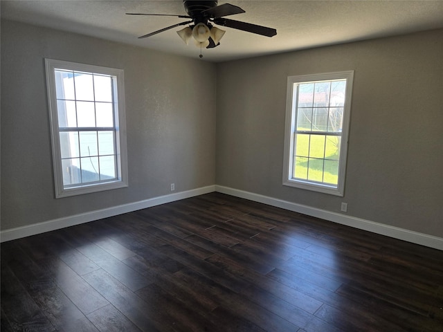 empty room featuring baseboards, dark wood-type flooring, a ceiling fan, and a textured ceiling