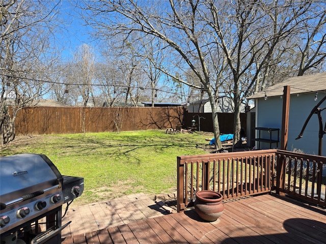 wooden deck with grilling area, a lawn, and a fenced backyard