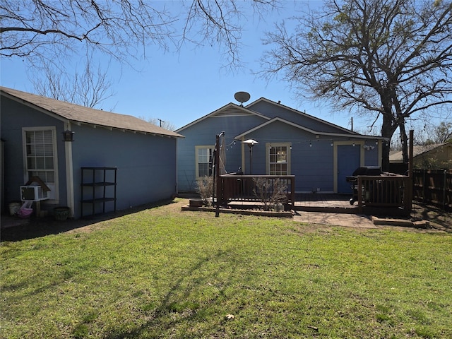 back of property with a lawn, a wooden deck, and fence