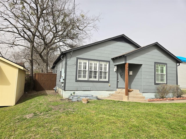 bungalow with a front yard, fence, and an outbuilding