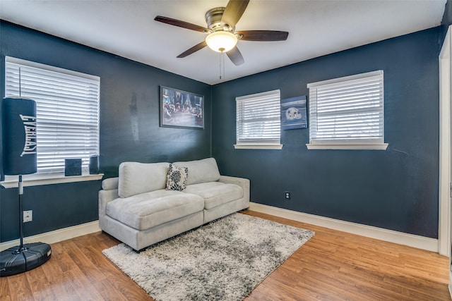 living area with a ceiling fan, baseboards, and wood finished floors