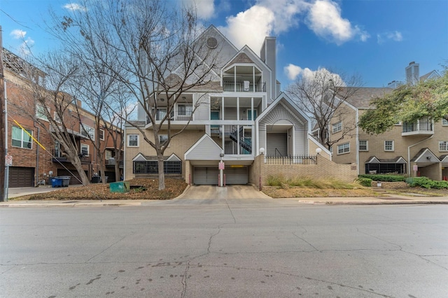 view of property with a garage, a balcony, and driveway