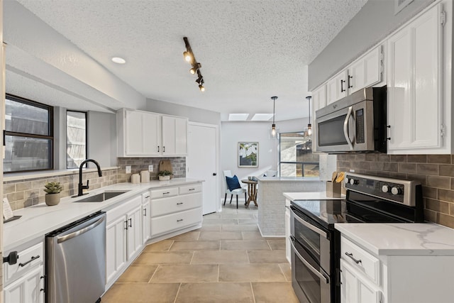 kitchen with a sink, backsplash, a textured ceiling, white cabinetry, and appliances with stainless steel finishes