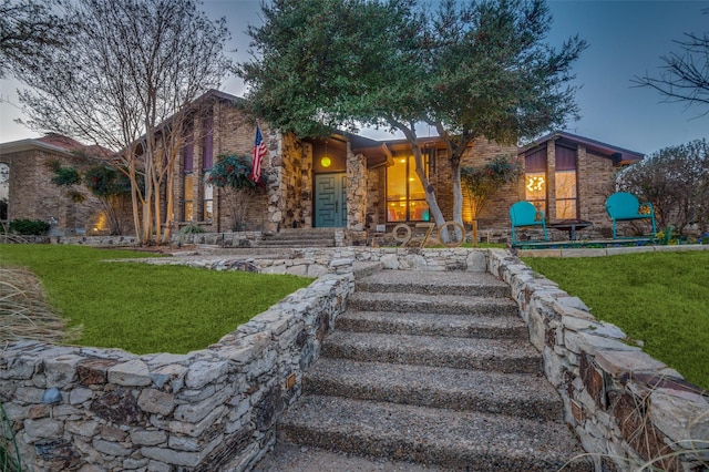 mid-century modern home featuring a front lawn, brick siding, and stone siding