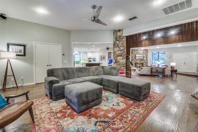 living room with visible vents, a stone fireplace, ceiling fan, and wood-type flooring