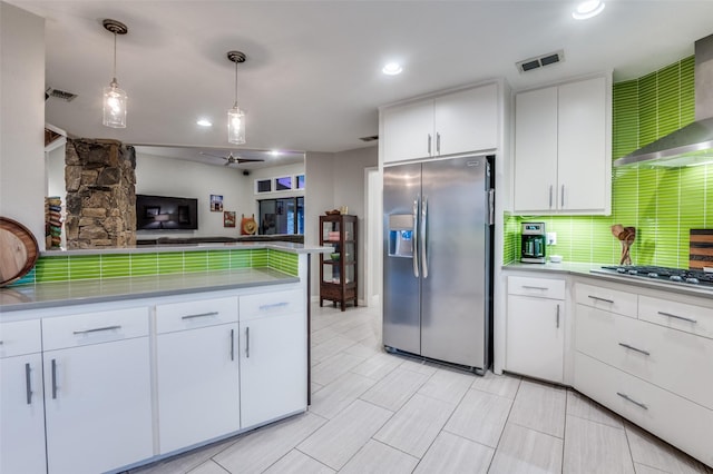 kitchen with wall chimney range hood, backsplash, visible vents, and appliances with stainless steel finishes