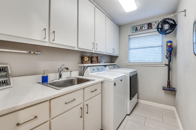 laundry area with washer and clothes dryer, cabinet space, baseboards, and a sink