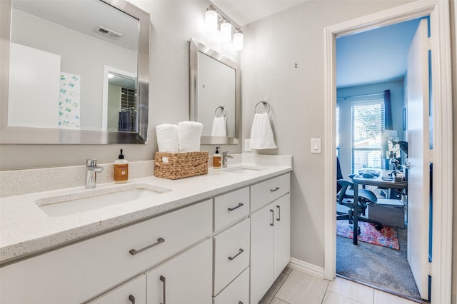 full bathroom featuring a sink, baseboards, and double vanity