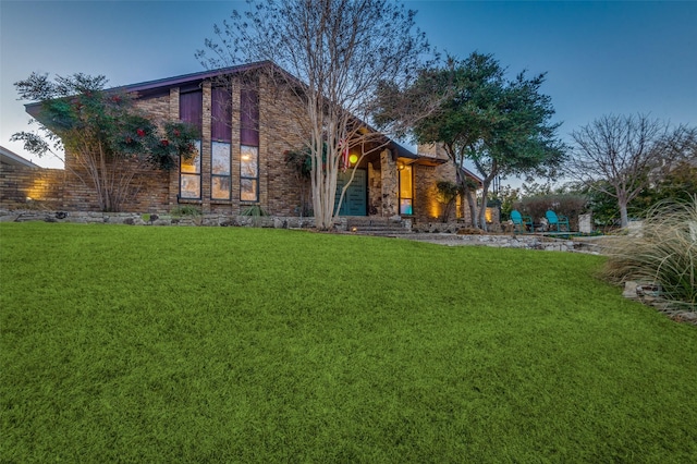 back of house with stone siding and a lawn