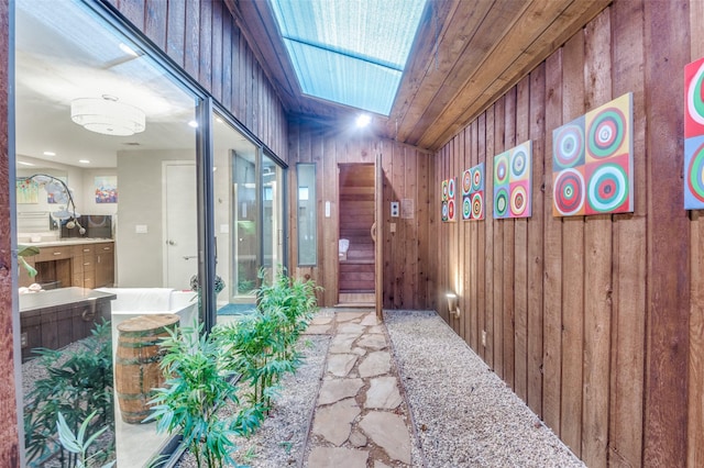 interior space featuring a skylight, wood ceiling, and wood walls