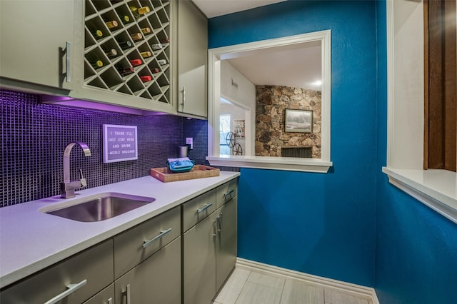 bar featuring tasteful backsplash, indoor wet bar, baseboards, and a sink