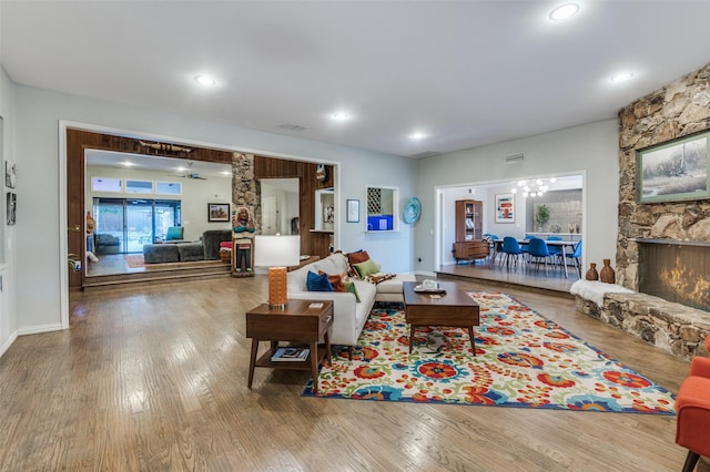 living area with a stone fireplace, recessed lighting, wood finished floors, and visible vents