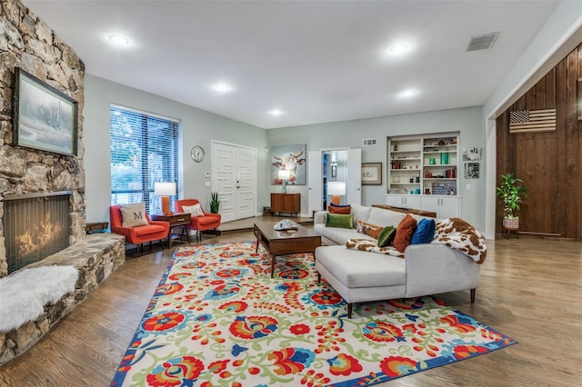 living area with a fireplace, recessed lighting, wood finished floors, and visible vents