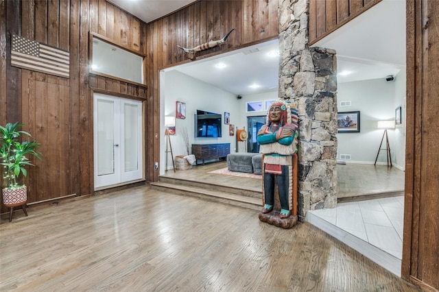 entryway featuring visible vents, wooden walls, wood finished floors, and a high ceiling