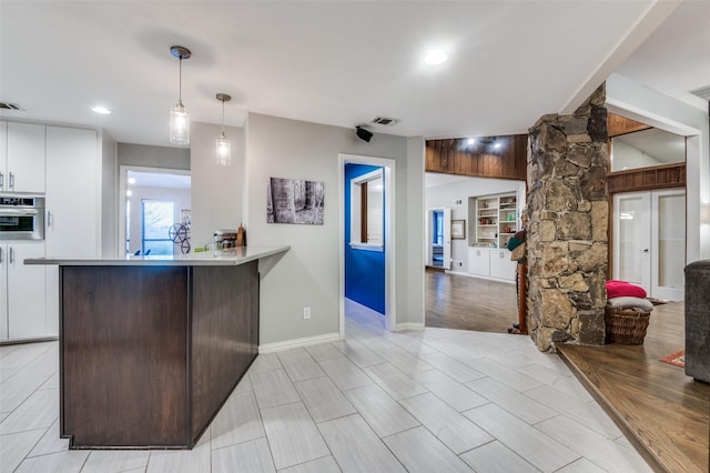 kitchen with decorative light fixtures, visible vents, white cabinetry, and oven