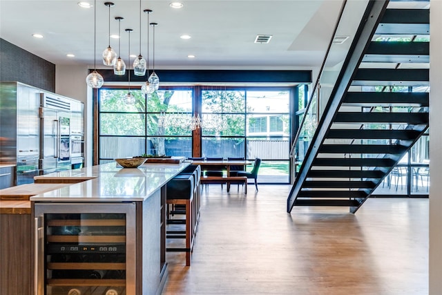 bar with wood finished floors, wine cooler, a healthy amount of sunlight, and built in fridge