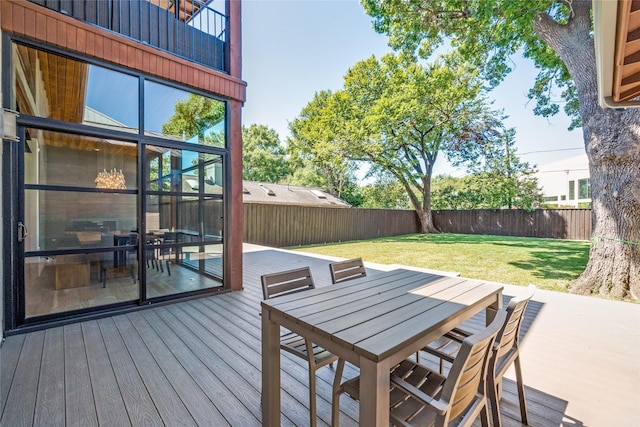 wooden deck with a fenced backyard, outdoor dining area, and a yard