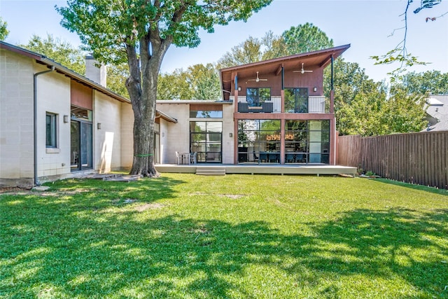 rear view of property with a balcony, fence, a lawn, and a chimney