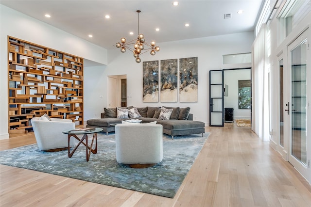 living room featuring a chandelier, a towering ceiling, and wood finished floors