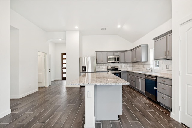 kitchen featuring wood finish floors, appliances with stainless steel finishes, gray cabinetry, and decorative backsplash