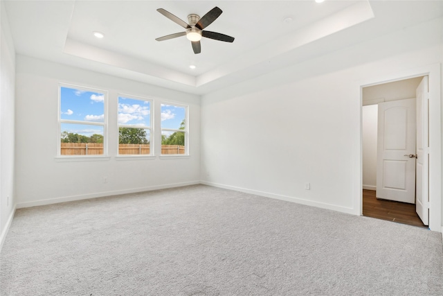 spare room featuring a ceiling fan, a tray ceiling, recessed lighting, carpet floors, and baseboards