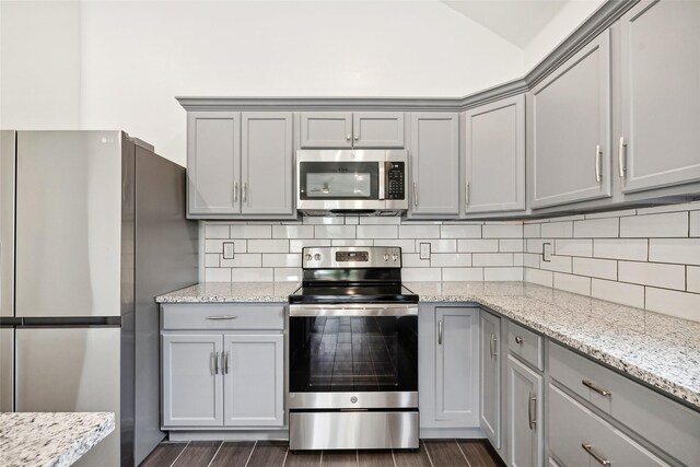 kitchen with tasteful backsplash, appliances with stainless steel finishes, and gray cabinetry