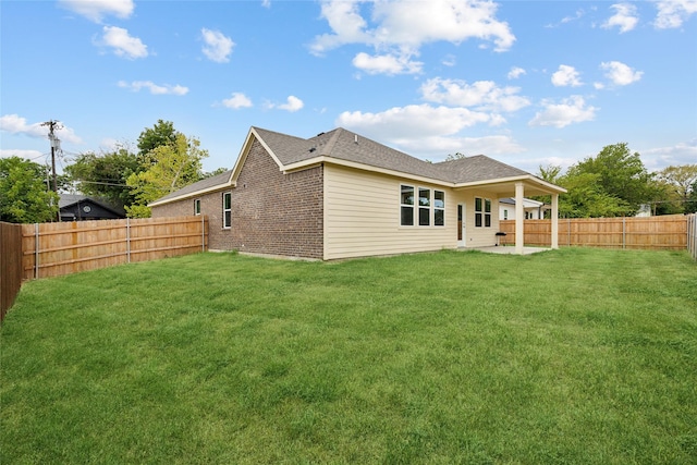 back of property with a patio, a yard, a fenced backyard, and brick siding