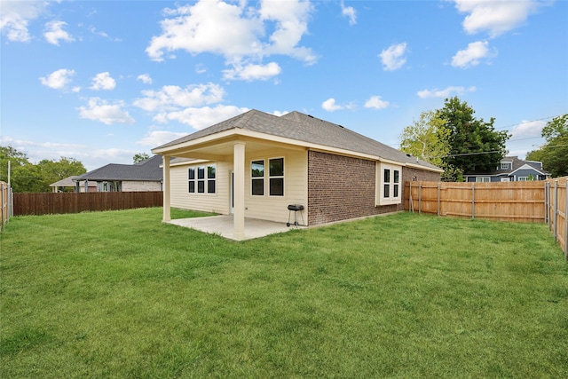 back of property with brick siding, a fenced backyard, a lawn, and a patio