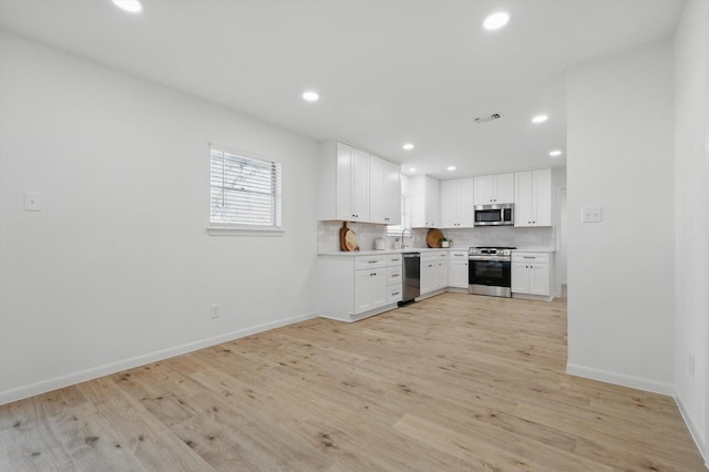 kitchen featuring light countertops, recessed lighting, light wood-style flooring, appliances with stainless steel finishes, and white cabinets