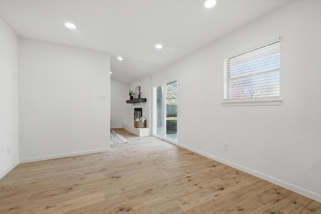 unfurnished living room with a brick fireplace, recessed lighting, light wood-type flooring, and baseboards