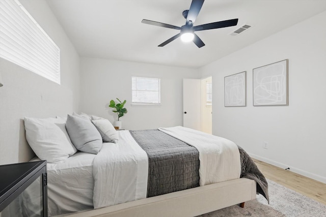 bedroom featuring ceiling fan, wood finished floors, visible vents, and baseboards