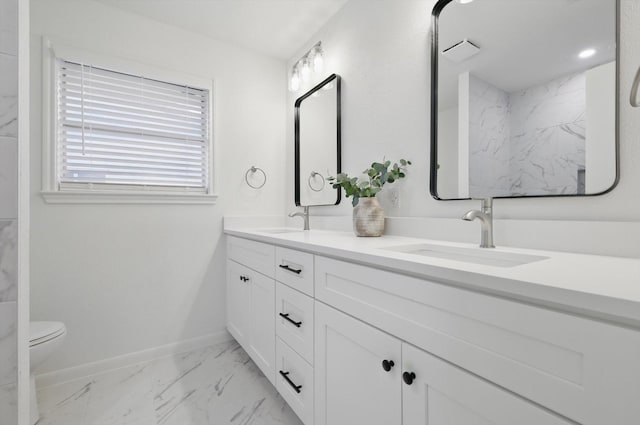 bathroom featuring double vanity, marble finish floor, baseboards, and a sink