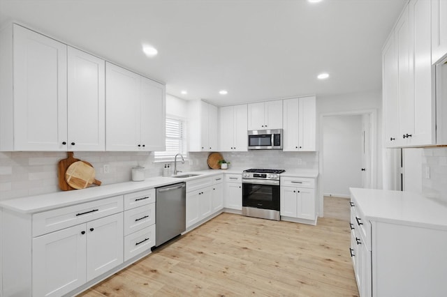 kitchen with light wood finished floors, decorative backsplash, stainless steel appliances, and a sink