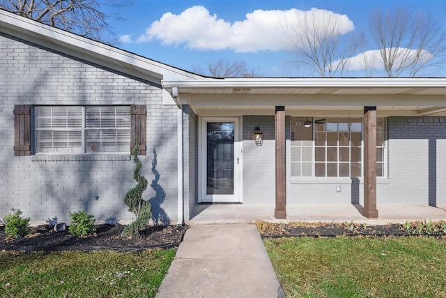 doorway to property with brick siding and a porch