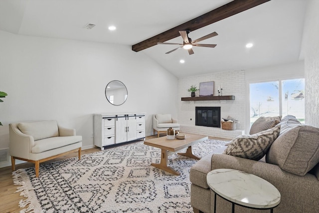 living room featuring wood finished floors, visible vents, lofted ceiling with beams, a fireplace, and recessed lighting