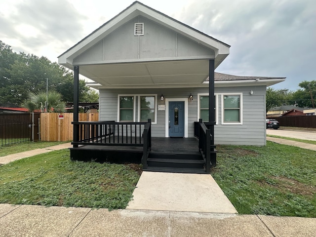 view of front of house featuring covered porch, a front yard, and fence