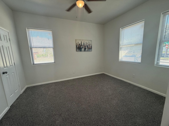 empty room featuring a ceiling fan, baseboards, and dark colored carpet