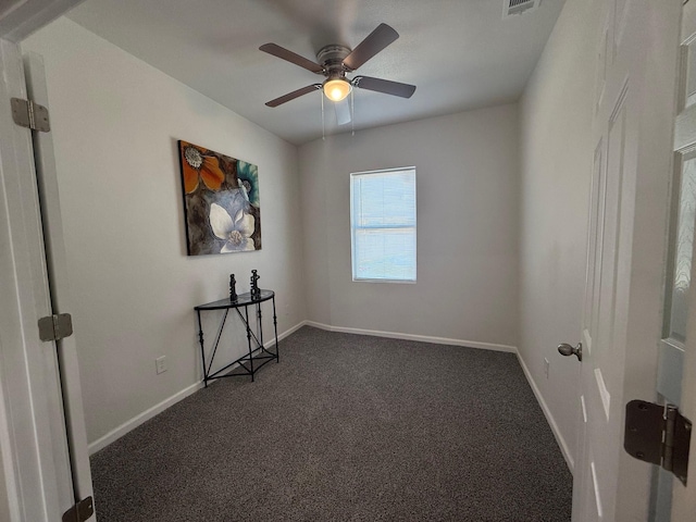 empty room featuring visible vents, dark carpet, baseboards, and ceiling fan