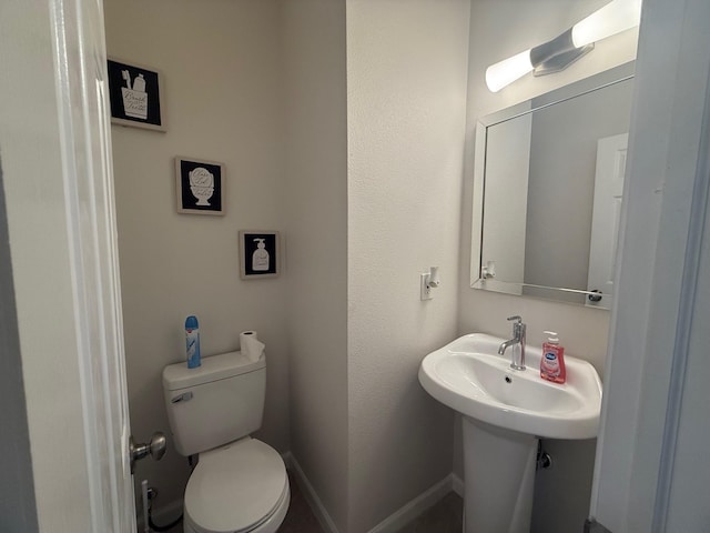 half bathroom with toilet and baseboards