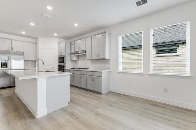 kitchen featuring visible vents, a sink, gray cabinetry, stainless steel appliances, and under cabinet range hood