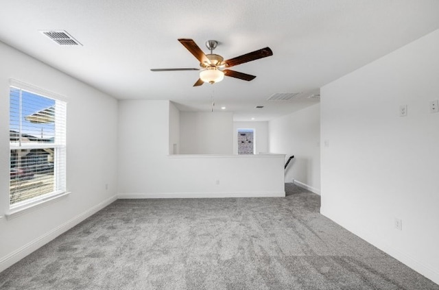 spare room featuring a ceiling fan, visible vents, carpet floors, and baseboards