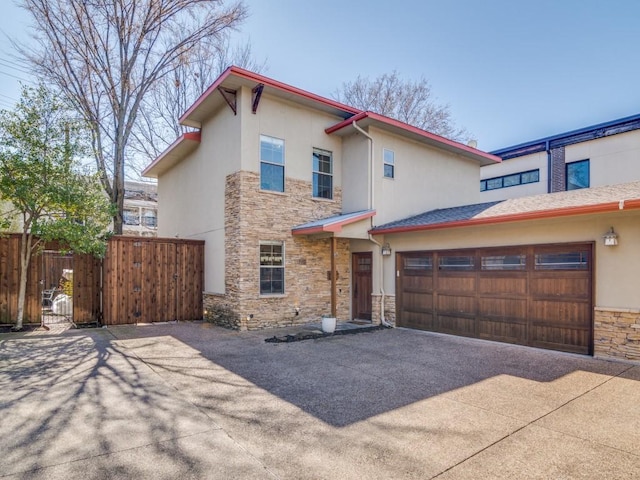 view of front of home featuring fence, stucco siding, stone siding, driveway, and a gate