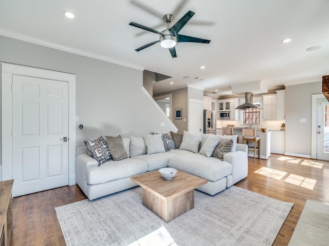 living room featuring crown molding, recessed lighting, wood finished floors, and baseboards