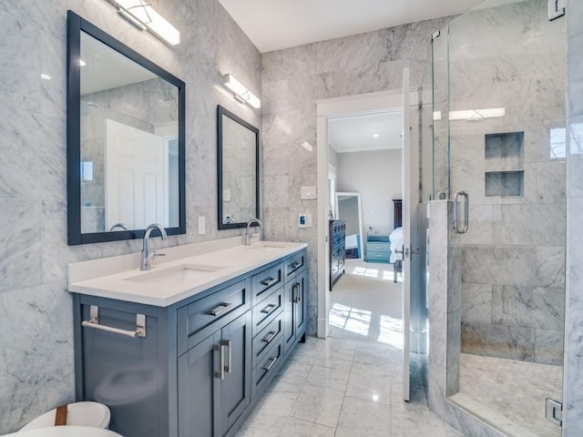 ensuite bathroom featuring a sink, tile walls, marble finish floor, and a shower stall