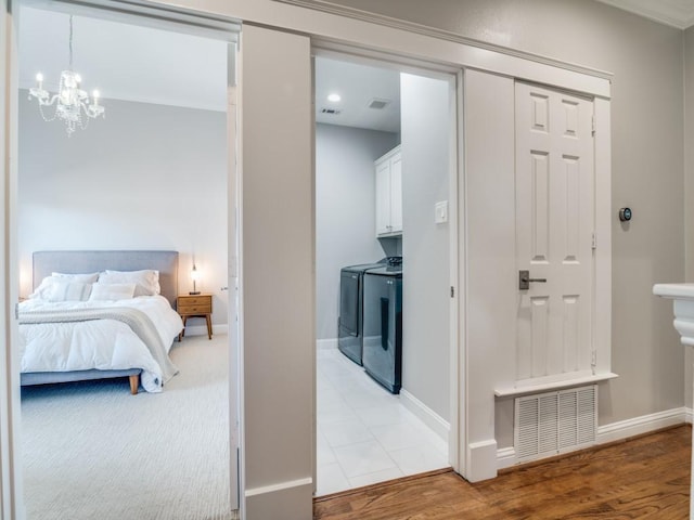 bedroom with independent washer and dryer, light wood-style floors, visible vents, and baseboards