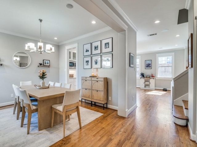 dining room with light wood-type flooring, visible vents, ornamental molding, stairway, and baseboards